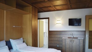 Una camera da letto con un letto, un armadio, una toeletta e una televisione appesa al muro.