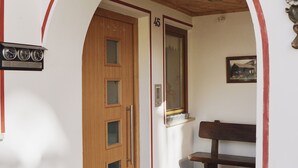 Un corridoio con una porta in legno con la scritta '45', una panca, un orologio a parete e una piccola finestra.
