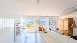 A modern kitchen with a large island, a dining area with a view, and a wooden cabinet. - NICE 130m2 Terrace with PANORAMIC VIEW, Swimming Pool, Free Parking, A/C, WIFI (Nice)