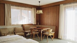 A room with a bed, a wooden dining table with chairs, a bench, and a hanging lamp. - Holiday Apartment '2' with Mountain View, Shared Garden and Wi-Fi (Ortisei)