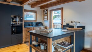 A modern kitchen with wooden beams, a central island, and built-in appliances.