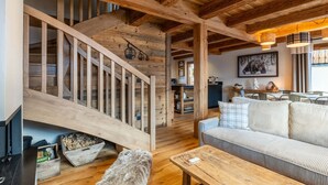 A wooden interior with a staircase, a sofa, and a dining area.