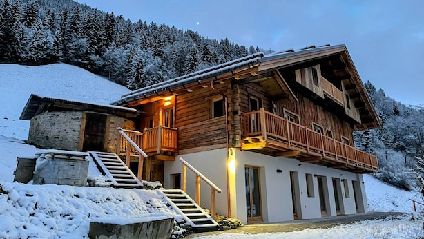 Una cabaña de madera con balcón, una escalera y un paisaje cubierto de nieve.