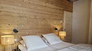 Una habitación con paneles de madera, una cama, dos lámparas de pared y una mesita de noche.