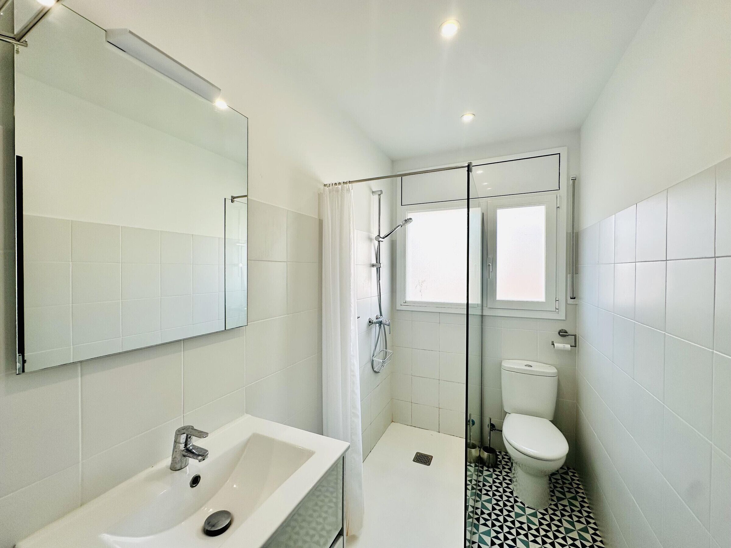 A modern bathroom with a glass-enclosed shower, a white sink, and a toilet.