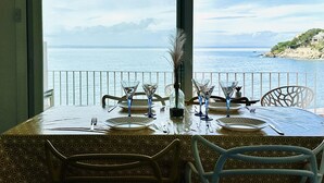 A dining table set for four with a view of the sea and a rocky coastline. - Spacious apartment in Roses near the beach with parking. (Roses)