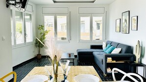 A modern living room with a sofa, a dining table with chairs, and a large window. - Spacious apartment in Roses near the beach with parking. (Roses)