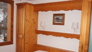 Un lit en bois avec deux oreillers blancs et une tête de lit ornée d’un décor en bois.