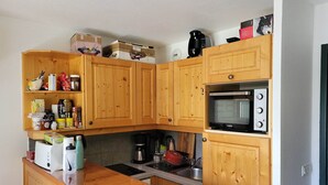 Une cuisine compacte avec des meubles en bois, un four à micro-ondes encastré et une machine à café.