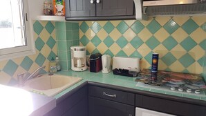 A kitchen with a window, a coffee maker, a toaster, and a refrigerator.