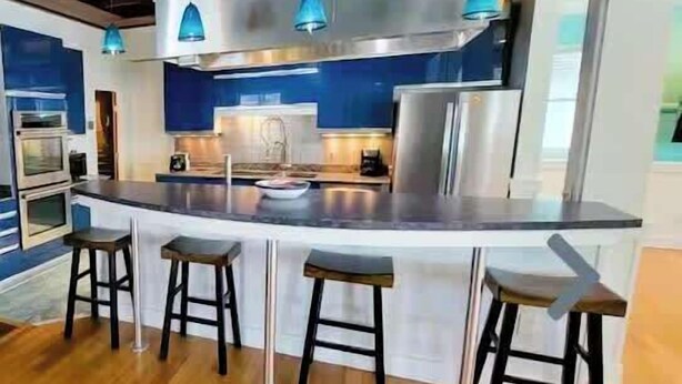 Een moderne keuken met een centraal eiland, barkrukken en hanglampen.