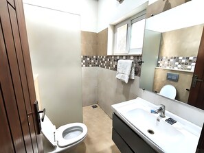 Habitación familiar | Baño | Regadera, pantuflas, toallas, papel de baño 