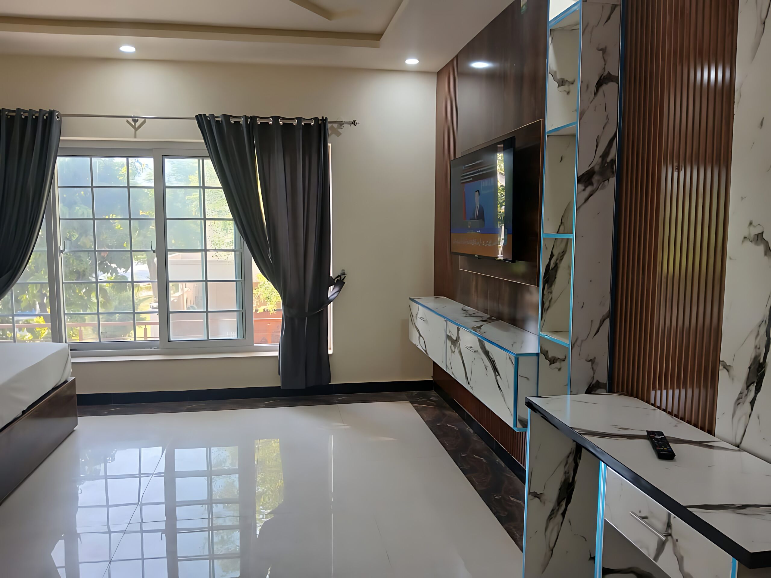 A modern room with a large window, a flat-screen TV, and a marble-patterned cabinet.
