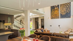 Ein modernes Wohnzimmer mit einem Holzesstisch, braunen Ledersofas und einer Treppe, die in einen oberen Bereich führt.