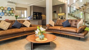 Ein modernes Wohnzimmer mit zwei braunen Ledersofas, einem runden Couchtisch und einer dekorativen Vase.