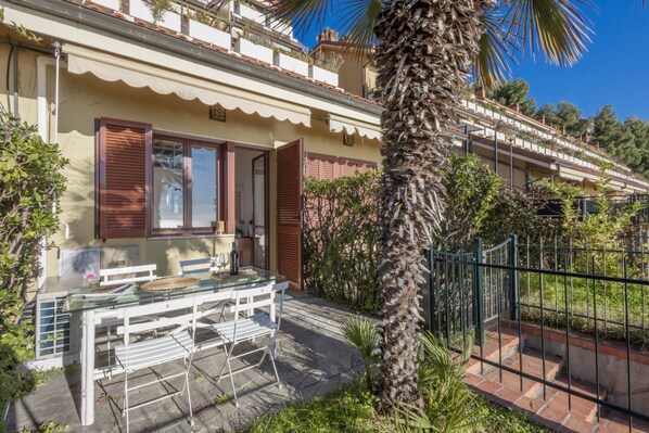 Un immeuble résidentiel doté d’un balcon, d’un palmier et d’une table avec des chaises à l’extérieur.