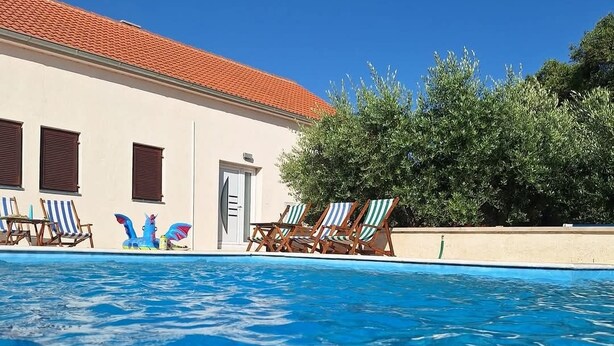 Una piscina con sillas de descanso y un edificio con tejado de baldosas.