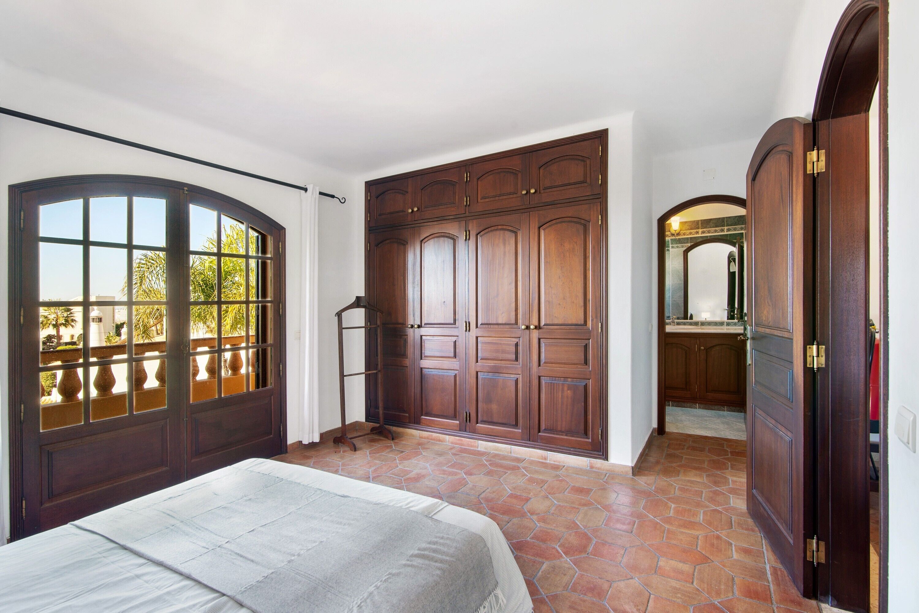 A bedroom with a bed, a wardrobe, and a bathroom visible through an open door.