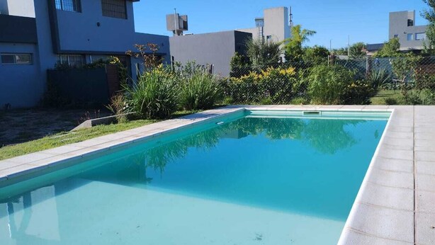 A rectangular swimming pool with a clear blue water surface, surrounded by a concrete deck and a low brick wall. - 20 minutes from Rosario! Ideal house to disconnect from the routine.  (Santa Fe)