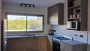 A modern kitchen with a large window, built-in cabinets, a microwave, and a stove. - 20 minutes from Rosario! Ideal house to disconnect from the routine.  (Santa Fe)
