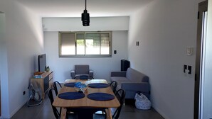 A compact living space with a dining area, a sofa, a TV, and a window with blinds. - 20 minutes from Rosario! Ideal house to disconnect from the routine.  (Santa Fe)