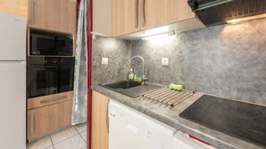 A kitchen with wooden cabinets, a Bosch dishwasher, a microwave, and a sink with a drying rack.