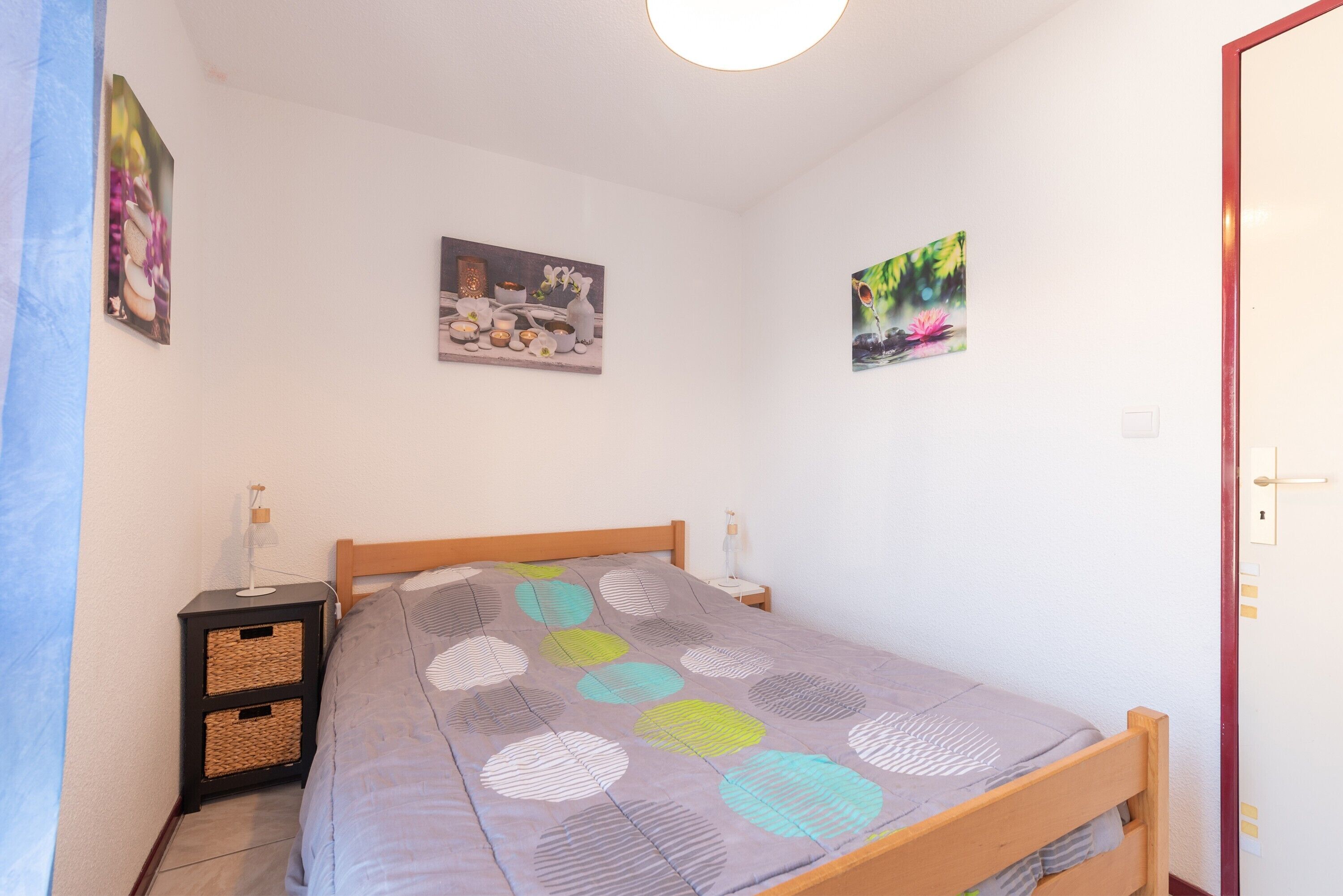 Een slaapkamer met een bed, nachtkastjes, wanddecoratie en een deur.