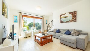 A living room with a sofa, a coffee table, a TV, and a large window with curtains.