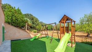 A playground with a wooden swing set and two green slides.