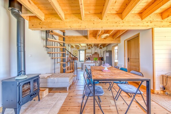 Un intérieur en bois avec une table à manger centrale, un escalier et un coin cuisine.