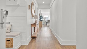 A hallway with a bench, a telephone, a lamp, and a mirror on the wall. - Award-Winning Resort Amenities | Ocean Club 4102 (Isle of Palms)