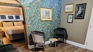 A cozy living room with a sofa, a wooden coffee table, and a patterned wallpaper. - The Fighting Cocks  (Fordingbridge)