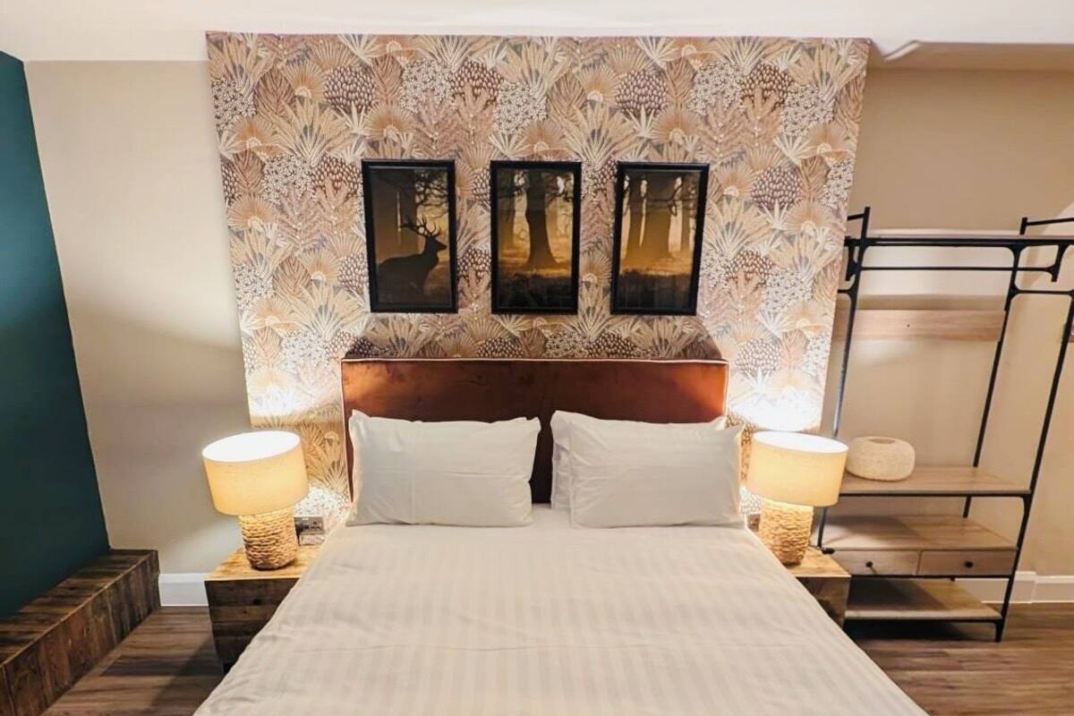 A neatly made bed with white linens, a wooden headboard, and two bedside lamps.