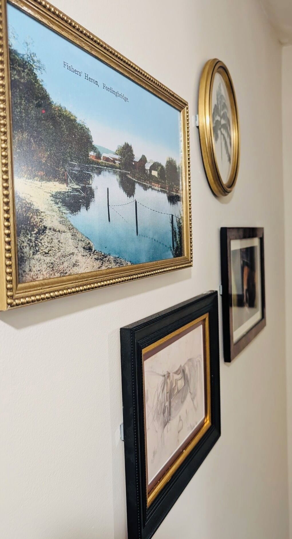 Una pared con tres cuadros: un paisaje, un retrato y una obra abstracta pequeña.