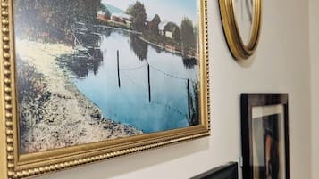 Una pared con tres cuadros: un paisaje, un retrato y una obra abstracta pequeña.