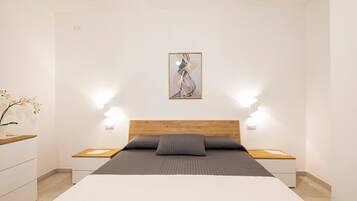 Ein Schlafzimmer mit einem Bett, Nachttischen, einer Wanddekoration und einer Vase mit Blumen.