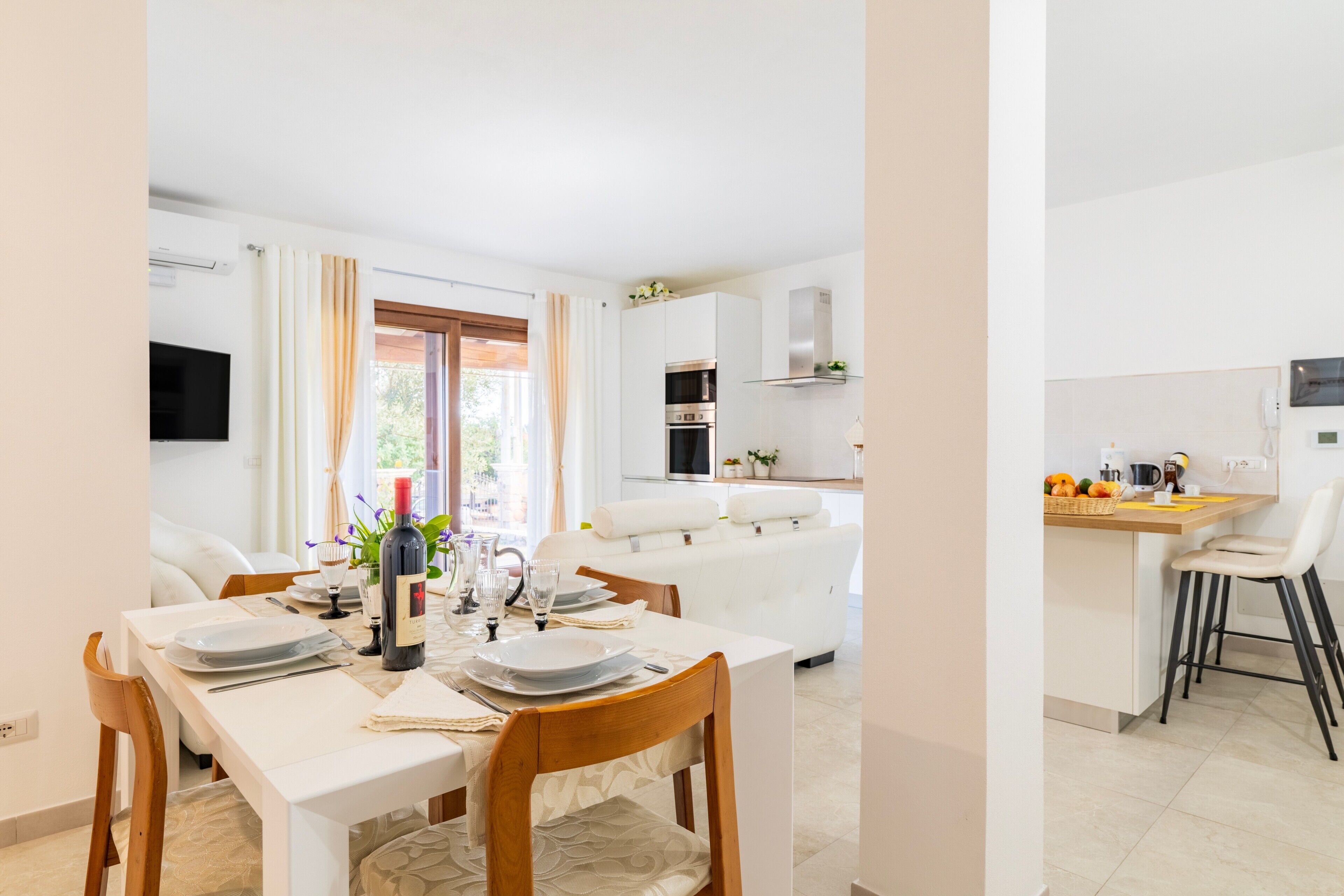 A modern kitchen with white cabinets, a microwave, and a dining area with a table set for two.