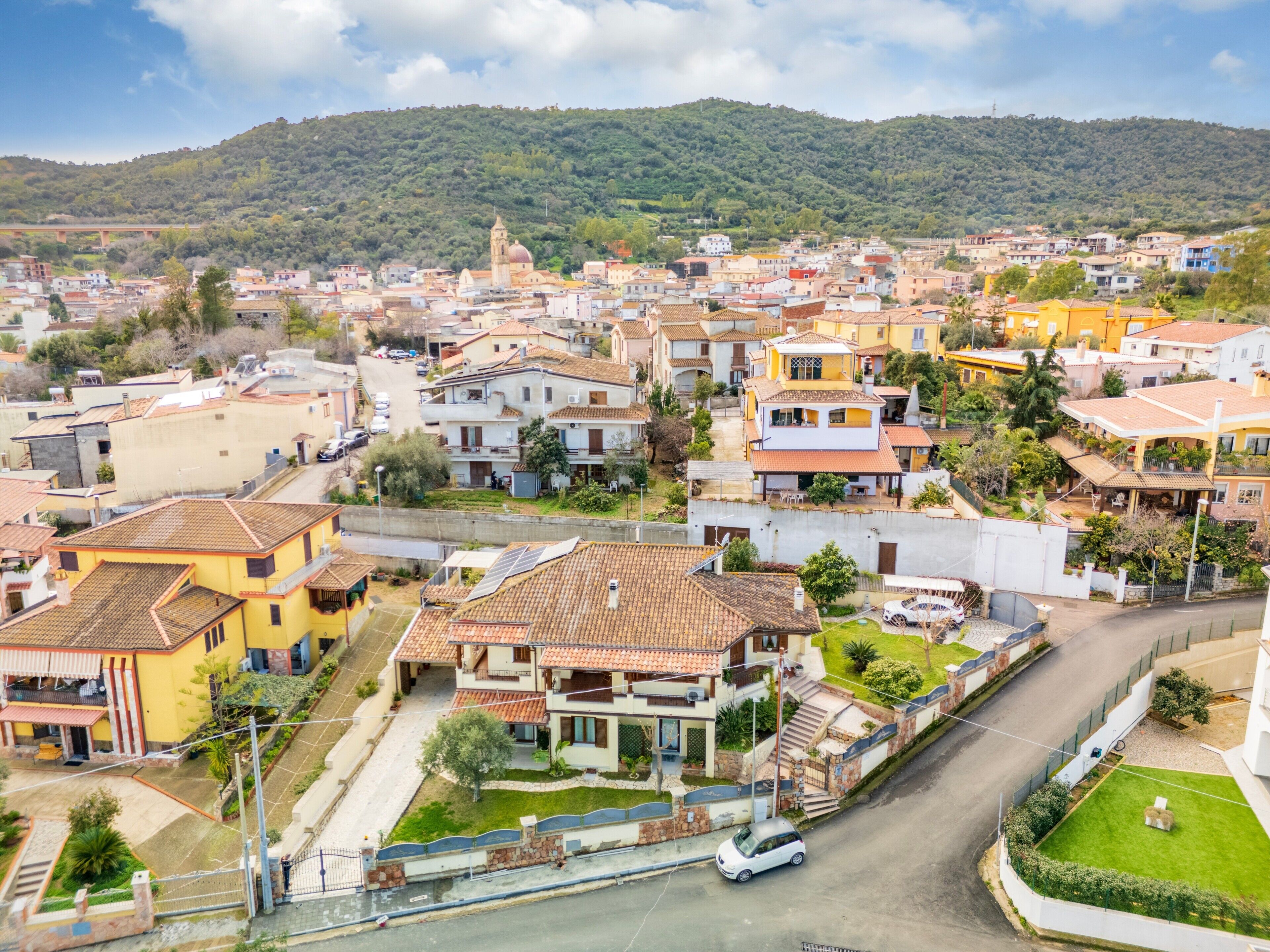 A residential area with houses, a church, and a bridge in the background.