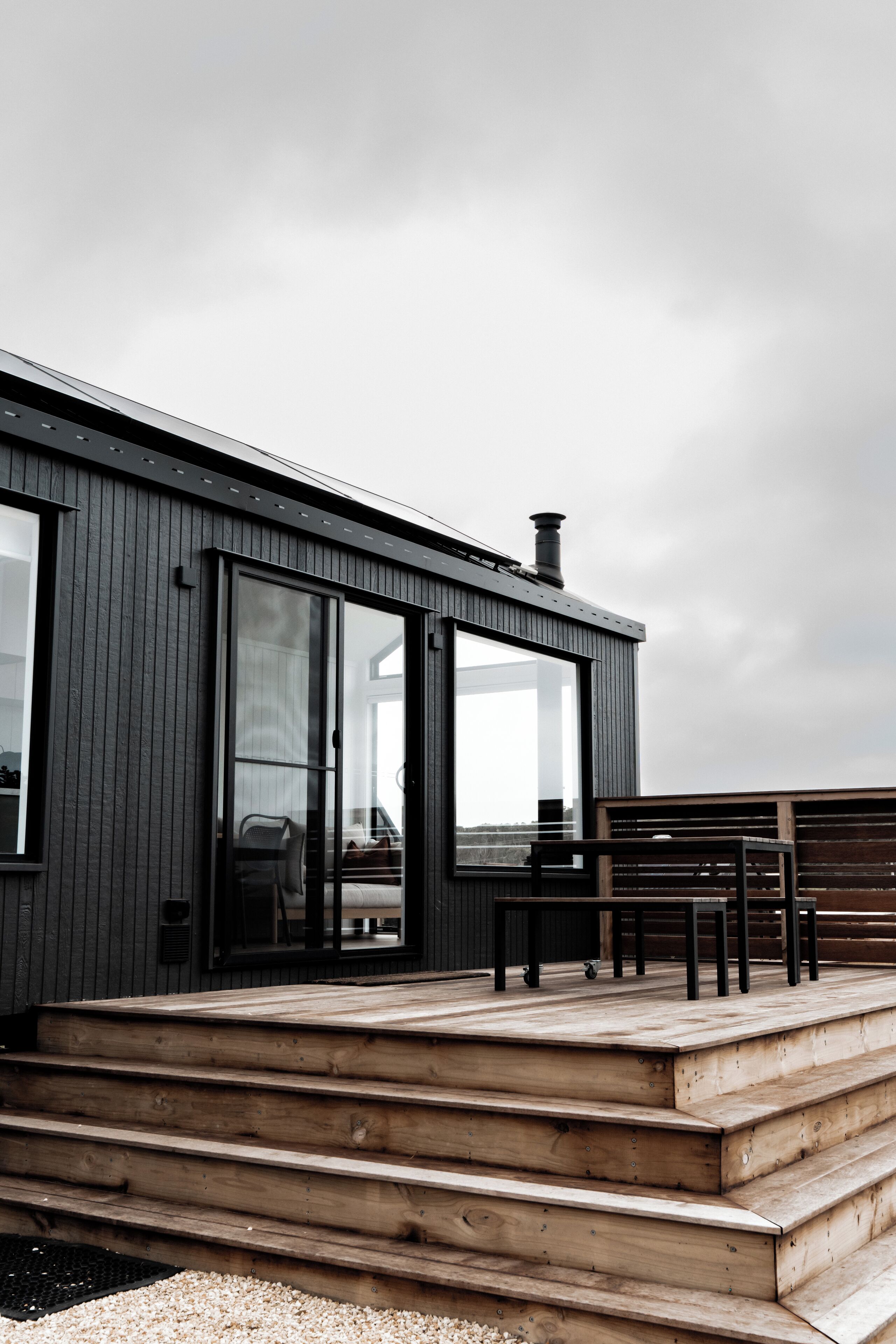 A modern building with a wooden deck, large sliding glass doors, and a chimney.