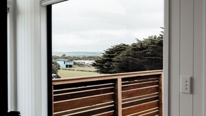 Una habitación con un ventanal grande que da a una terraza de madera y vistas de un paisaje lejano.