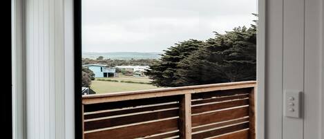 A room with a large window overlooking a wooden deck and a view of a distant landscape.