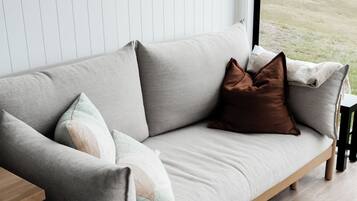 Una sala de estar moderna con un sofá, cojines y vistas al exterior.