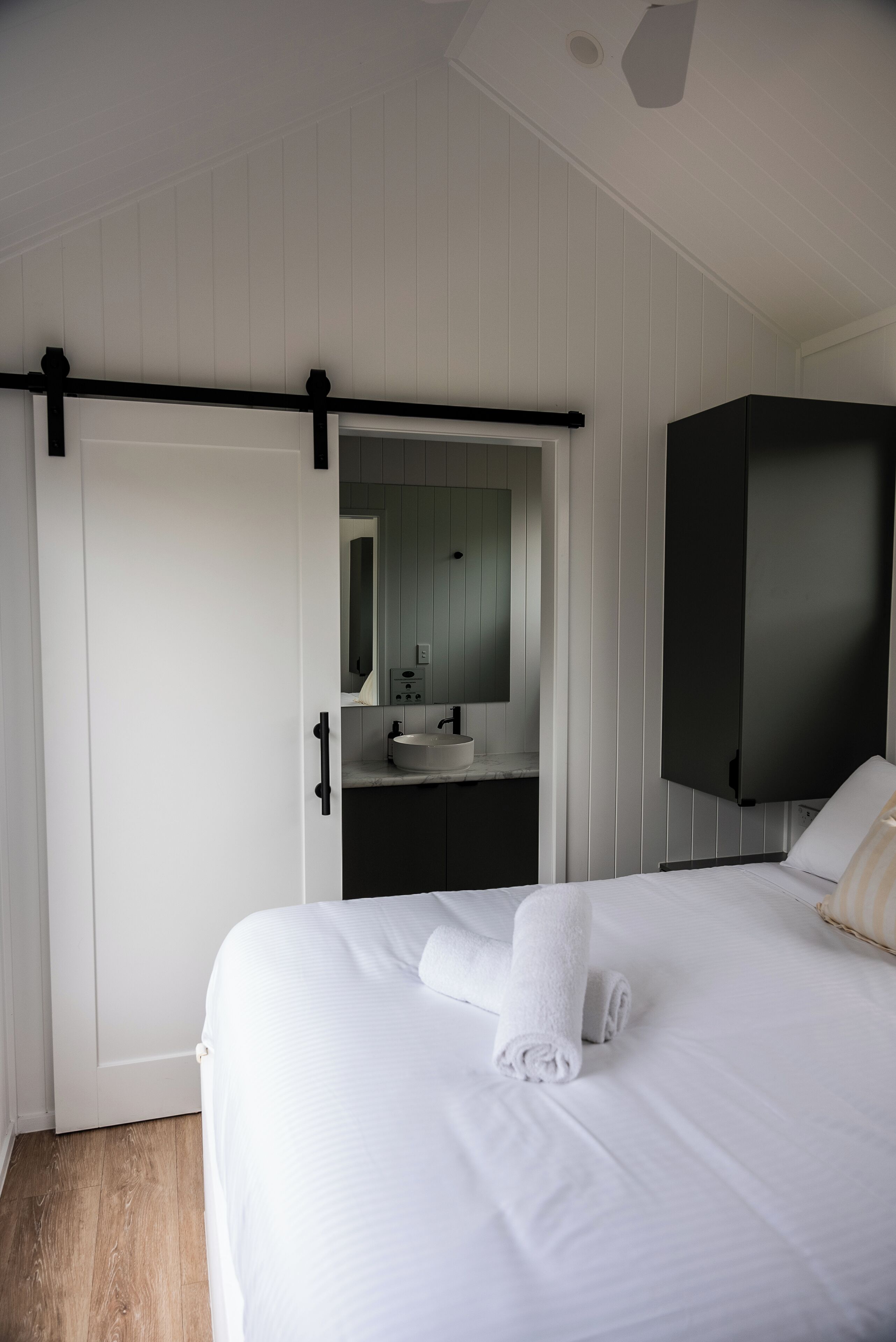 A bedroom with a bed, a bathroom with a sink and mirror, and a wardrobe.