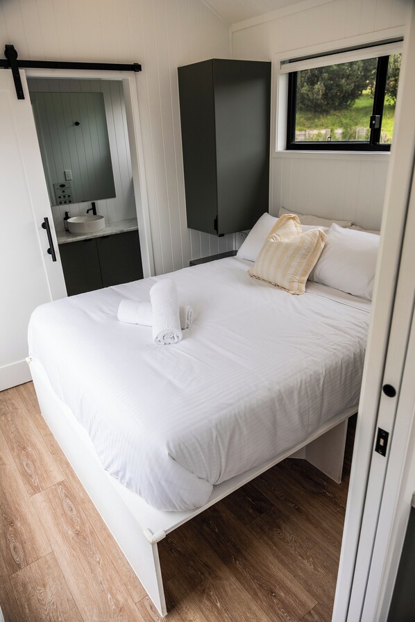 A bedroom with a bed, a window, a bathroom, and a wardrobe. - Swell At Cape Bridgewater (Cape Bridgewater)