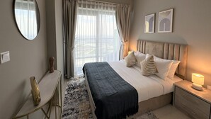 A bedroom with a bed, bedside table, lamp, and a view of the city through the window. - Easygo-cozy 1bdr Zada Tower (Dubai)