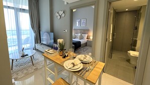 A modern hotel room with a dining area, a bed with a view, and a shower. - Easygo-cozy 1bdr Zada Tower (Dubai)
