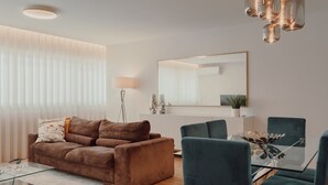 A modern living room with a brown sofa, a glass dining table, and teal chairs. - Apartment 'Lux In Porto' with Wi-Fi and Air Conditioning (Porto)