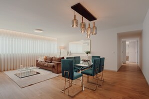 Una sala de estar moderna con una mesa de centro de vidrio, un sofá y un comedor con sillas.