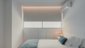 A bedroom with a bed, a nightstand, a lamp, and an air conditioning unit. - Apartment 'Lux In Porto' with Wi-Fi and Air Conditioning (Porto)