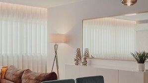 A modern living room with a sofa, a dining table with chairs, a floor lamp, and a large mirror. - Apartment 'Lux In Porto' with Wi-Fi and Air Conditioning (Porto)